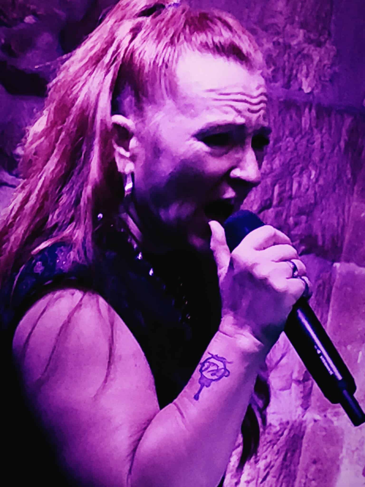 Mujer cantando en escenario con micrófono