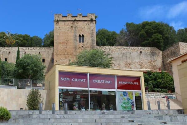 Fachada moderna frente a castillo histórico en Mallorca.
