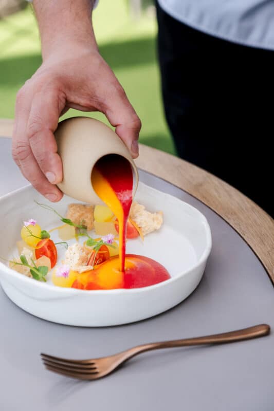 Mano vertiendo salsa roja y amarilla gourmet