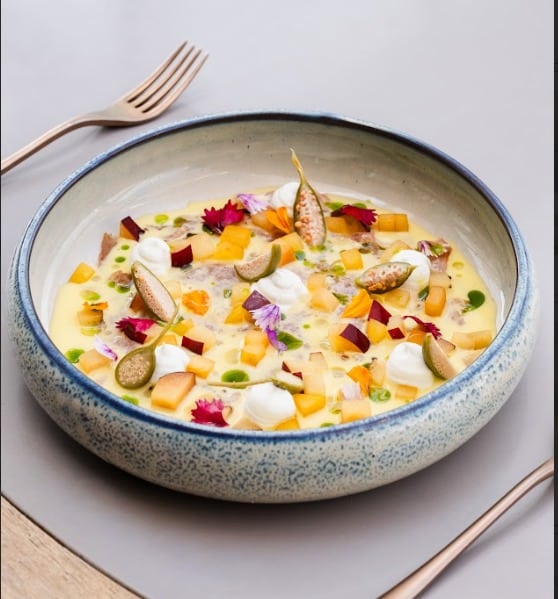 Plato de sopa cremosa con verduras y flores