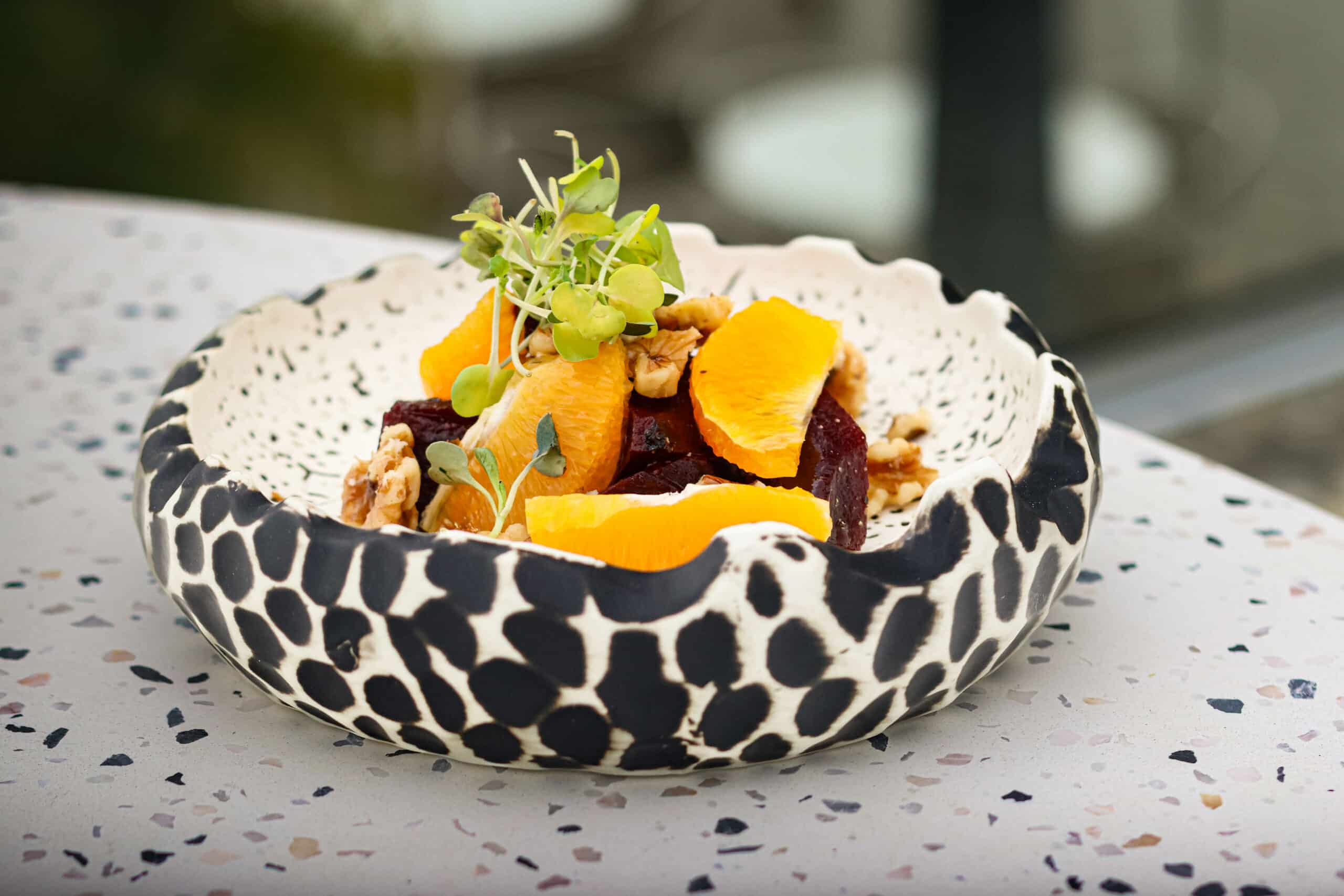 Ensalada de naranja, remolacha y nueces en cuenco artesanal