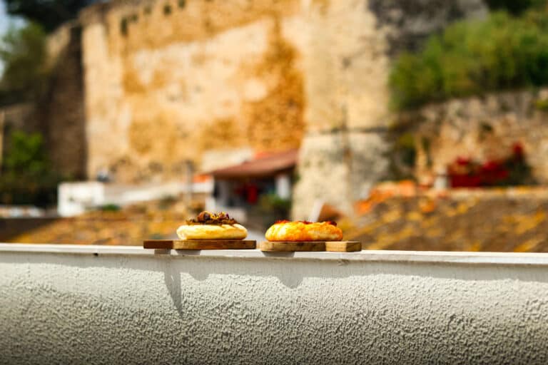 Dos mini pizzas en tablas de madera con edificio histórico al fondo