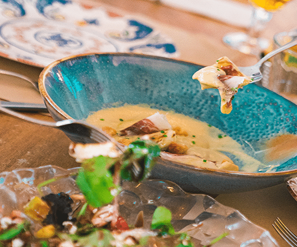 Plato gourmet en cuenco azul turquesa sobre mesa de restaurante