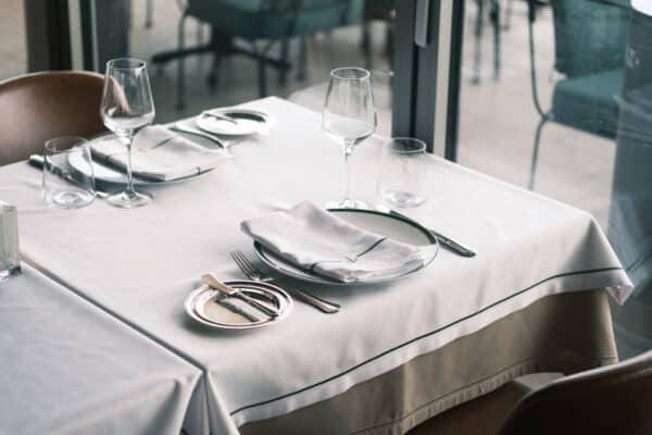 Mesa de restaurante elegante con mantel blanco y cubiertos